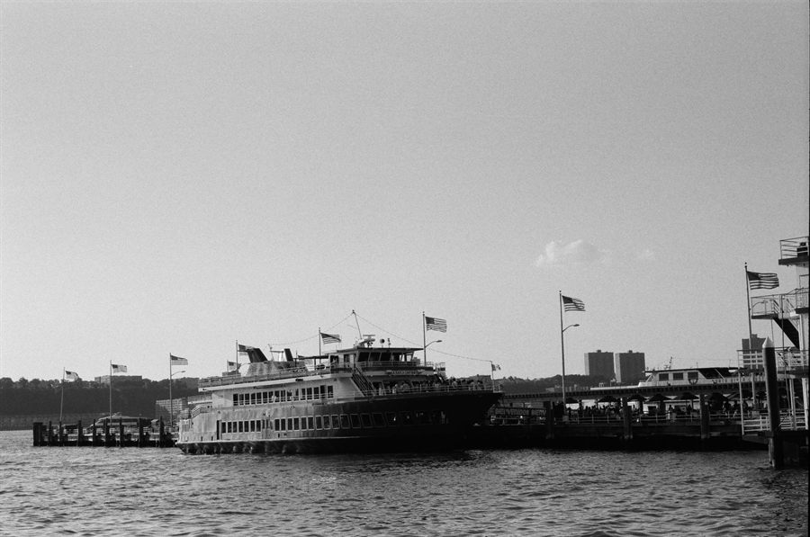 Black-and-white view of a docked excursion boat lined with American flags