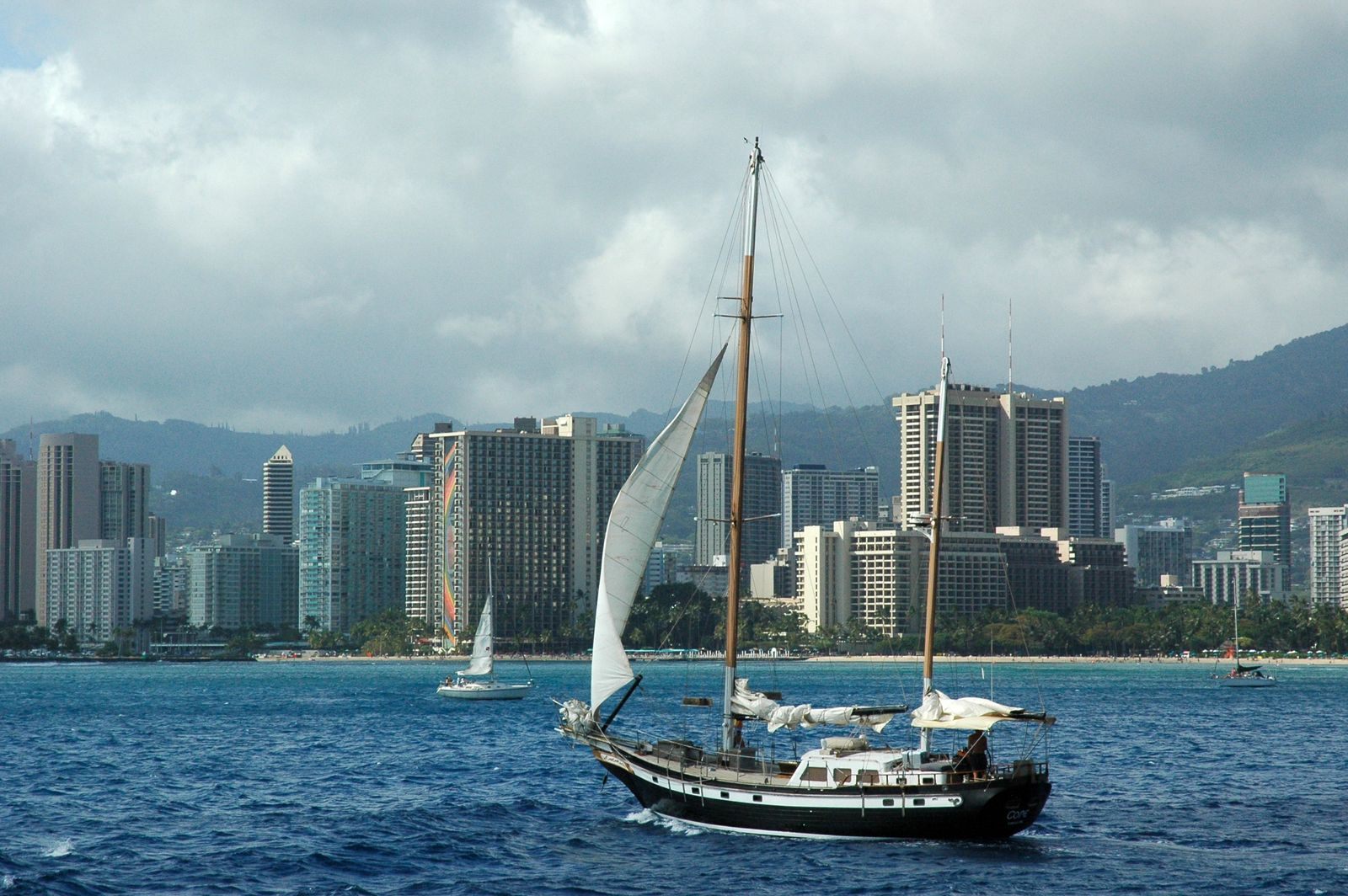 Sailboat on the water off the Honolulu skyline with green mountains behind