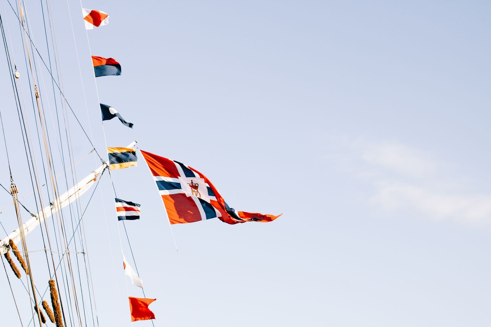Signal flags and pennants strung through a ship’s rigging against a pale sky, part of the answer to what flags do cruise ships fly