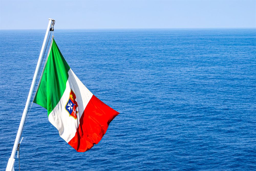 Italian maritime flag flying from a ship over the open blue Mediterranean