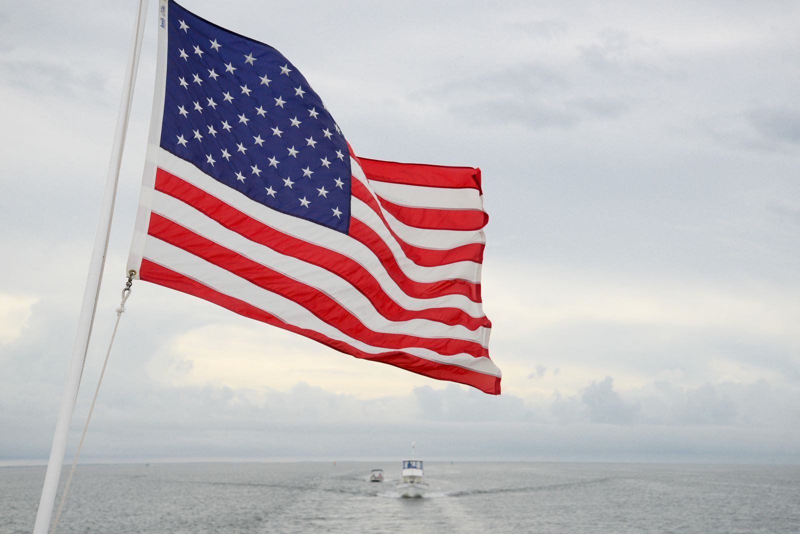 American flag flying from the stern of a boat at sea, a symbol of the question of which US cruise lines are really American